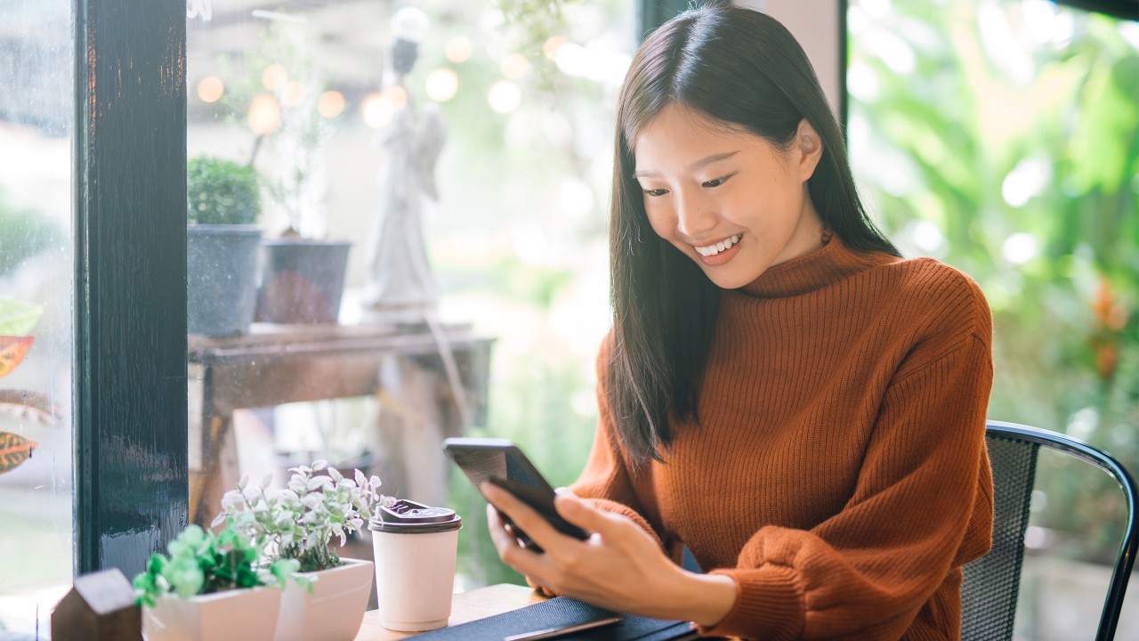 A girl is looking at a smartphone with smile;image used for HSBC mobile banking.