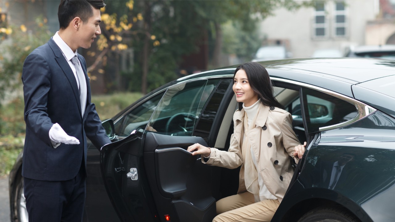 A man opens car door for a woman; Image used for HSBC free airport transfers page.