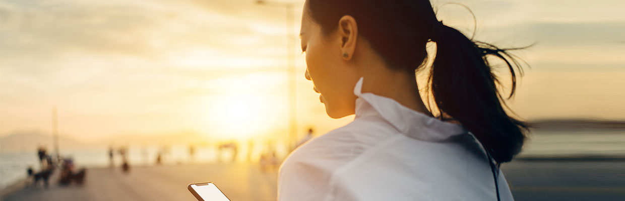 A lady is watching a smartphone;  image used for Monthly Investment Plan (MIP) Fund.