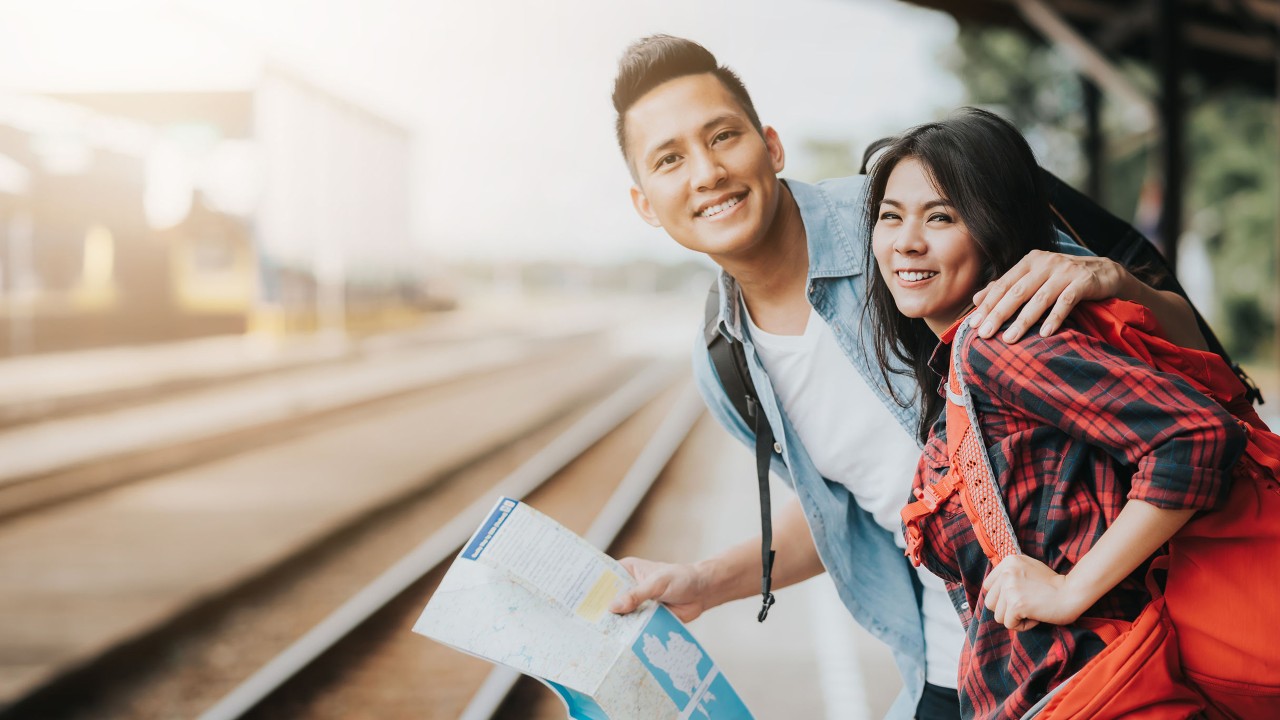 A man is holding a map and tapping on a woman's shoulder; image used for HSBC Taiwan travel insurance coverage page.