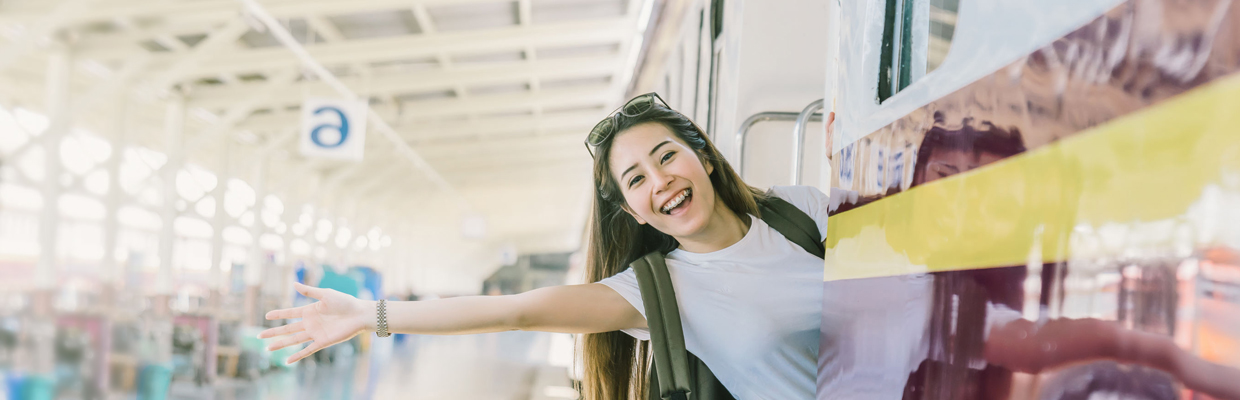 一個女人站在火車裡面，伸出上半身到火車外面愉快地揮手; 圖片使用於滙豐台灣道路救援及緊急代步車的頁面。