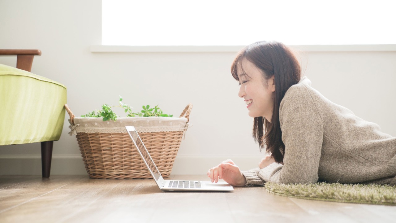 A lady is lying on the floor and using laptop; image used for HSBC Foreign Stock page.