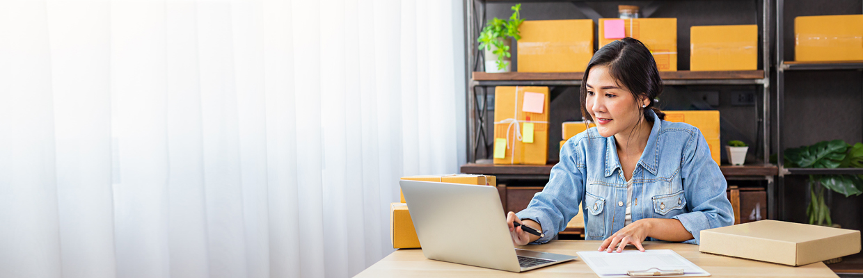 A lady is using a laptop and filling out documents; image used for Exchange Traded Funds (ETF).